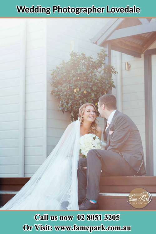 Photo of the Bride and the Groom looking each other while sitting on the staircase Lovedale NSW 2325