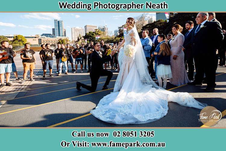 Groom Kneeling while holding the hands of the Bride Neath